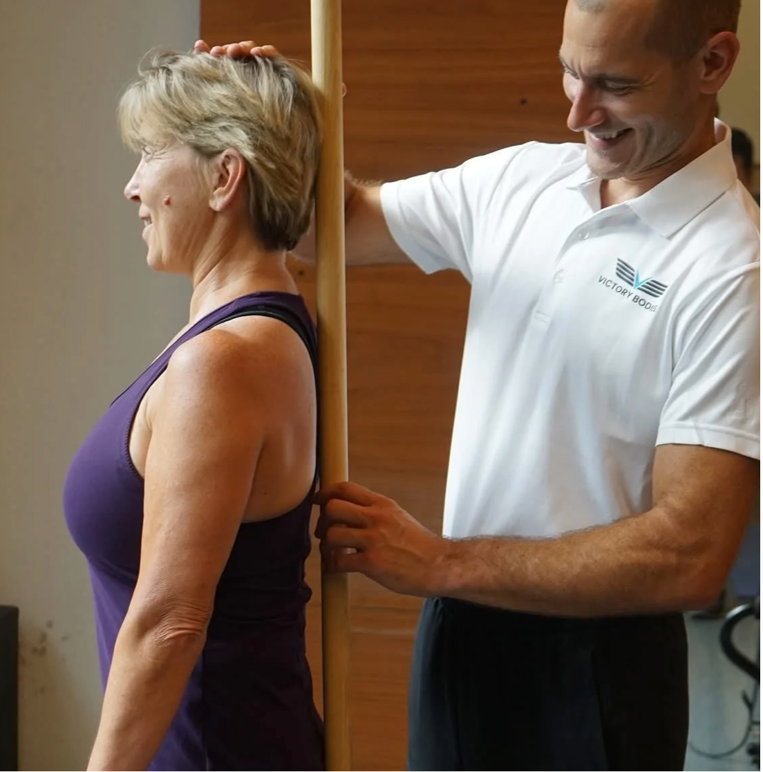 Matthew helping a client understand standing alignment using a dowel