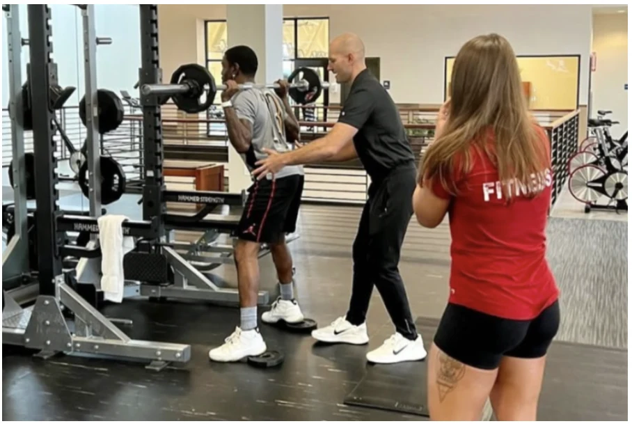 Matthew coaching a client through a barbell squat