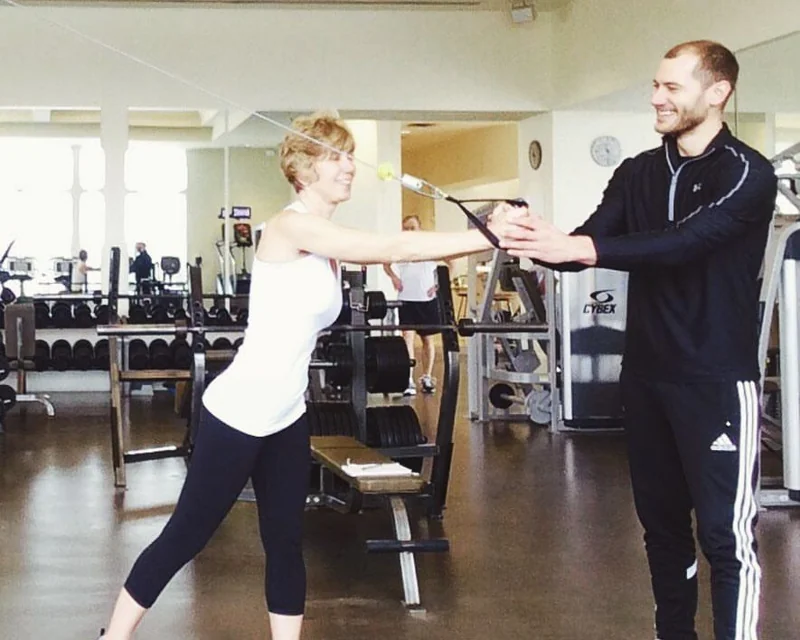 Matthew guiding his mother through a standing cable exercise