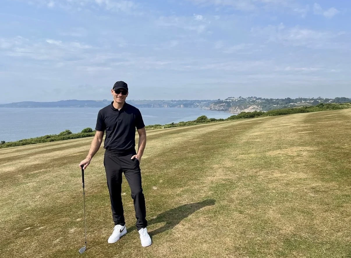 Matthew Carney holding a golf club on a coastal golf course