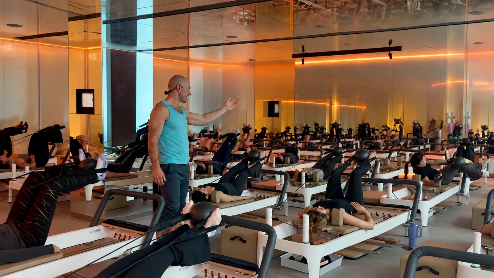 Matthew wearing a headset microphone while teaching a large reformer Pilates class